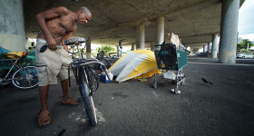 Oliver (only first name given) adjusts his bicycle near his tent under the H1 overpass, along Harding Avenue. homeless tents. 16 july 2015. photograph Cory Lum/Civil Beat