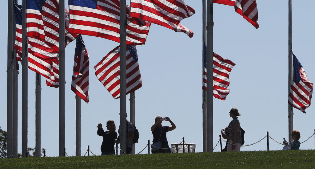 Visitors enjoy the Washington Monument with flags lowered to half staff after the deadliest shootings in US history.