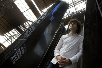 FILE - In this May 11, 2017, file photo, Dutch innovator Boyan Slat poses for a portrait next to the anchors of his plastic collecting system, suspended from the roof of a building in Utrecht, Netherlands. Engineers will deploy a trash collection device to corral plastic litter floating between California and Hawaii in an attempt to clean up the world's largest garbage patch in the heart of the Pacific Ocean. The 2,000-foot (600-meter) long floating boom will be towed Saturday, Sept. 8, 2018, from San Francisco to the Great Pacific Garbage Patch, an island of trash twice the size of Texas. The system was created by The Ocean Cleanup, an organization founded by Slat. (AP Photo/Peter Dejong, File)