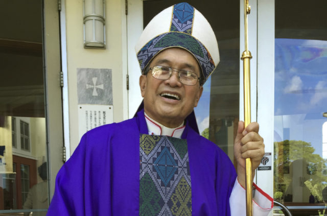FILE - In this Nov. 30, 2014 file photo, Archbishop Anthony Apuron stands in front of the Dulce Nombre de Maria Cathedral Basilica in Hagatna, Guam. On Thursday, April 4, 2019 the Vatican upheld its conviction of Guam's ousted archbishop Apuron for sexually abusing minors and has added a further penalty on appeal that effectively prevents him from presenting himself as a bishop. (AP Photo/Grace Garces Bordallo, File)