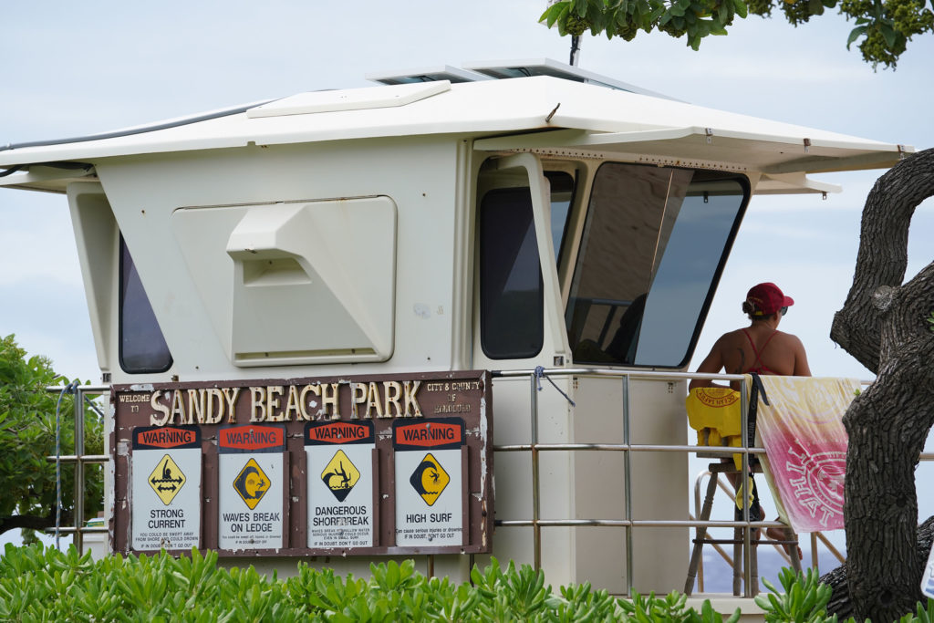Sandy Beach Park lifeguard tower with signs warning visitors.