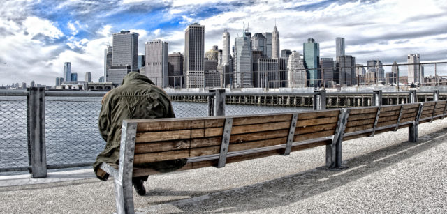 HDR Homeless Person On Bench Against Manhattan Cityscape In Daylight winter