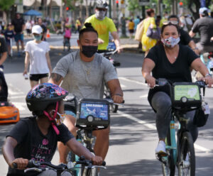 Honolulu residents wear masks as COVID precautionary measure while riding bikes on Kalakaua Avenue in Waikiki, HI. (Ronen Zilberman photo Civil Beat)