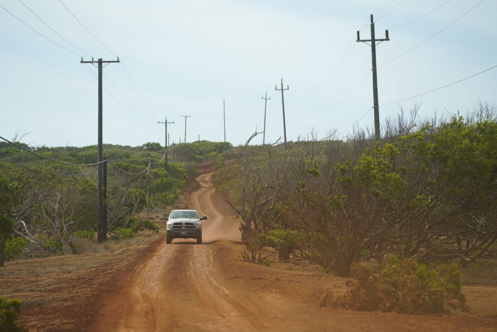 Red dirt road meandering down towards the Molokai Land Trust 's The Mokio Preserve located on the west side of Molokai.