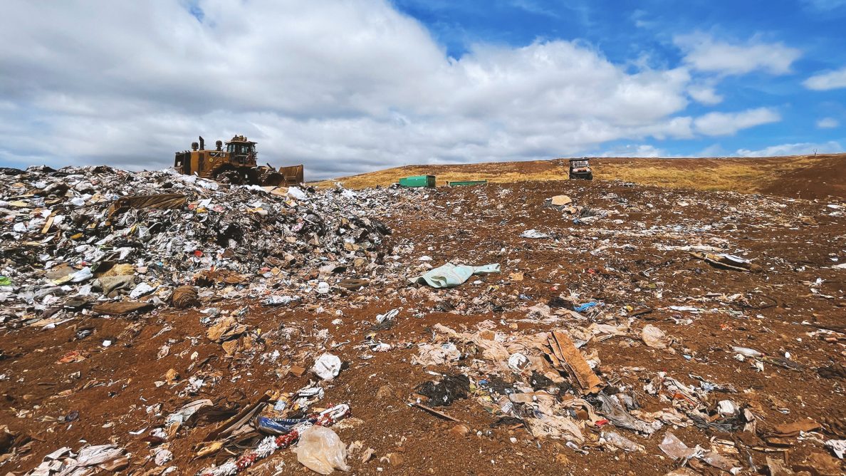 A bulldozer moves trash into mounds