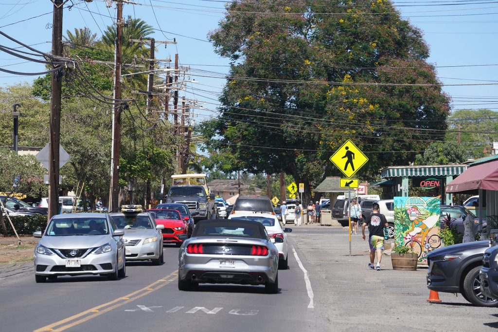 Pedestrians walk along Kamehameha Highway in Haleiwa town.