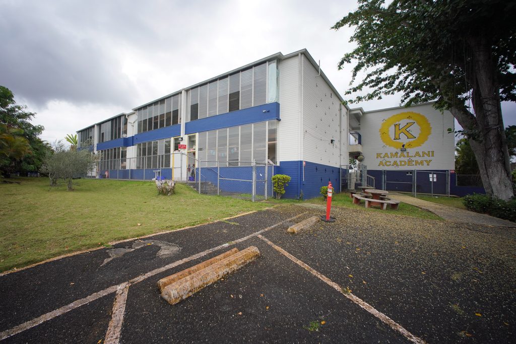 The Kamalani Academy charter school building painted in school colors blue and yellow. A large letter "K" and the name of the school "Kamalani Academy" is painted in yellow on the side of the building.