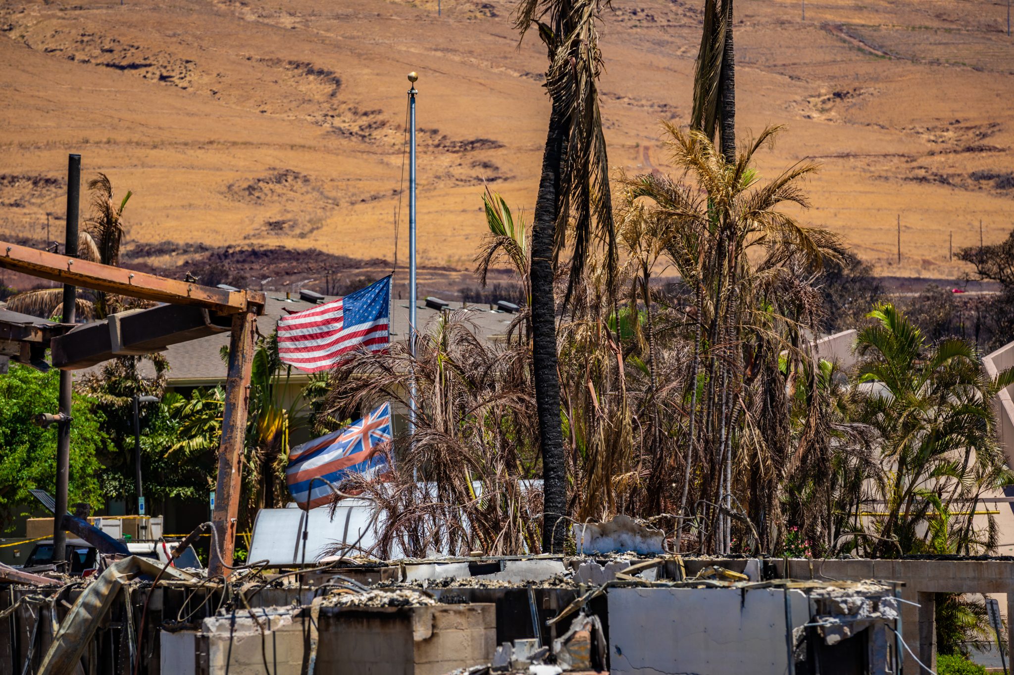 The U.S. Flag and State of Hawaii Flag fly at half-mast in Lahaina, Maui, Aug. 30, 2023. In support of Maui County authorities, JTF-50, composed of the Hawaii Army and Air National Guard, U.S. Army Active Duty, Reserve and U.S. Navy, is dedicated to the safety and recovery of affected Maui residents, coordinating with local first responders and adhering strictly to local, state, and federal guidelines and laws. (U.S. Army National Guard photo by Staff Sgt. Matthew A. Foster)