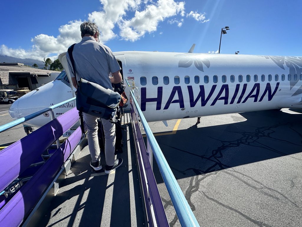 A passenger boards a Hawaiian Airlines inter-island Boeing 717s at the Ellison Onizuka Kona International Airport Thursday, Dec. 14, 2023, at Keāhole on the Big Island of Hawaii . (Kevin Fujii/Civil Beat/2023)