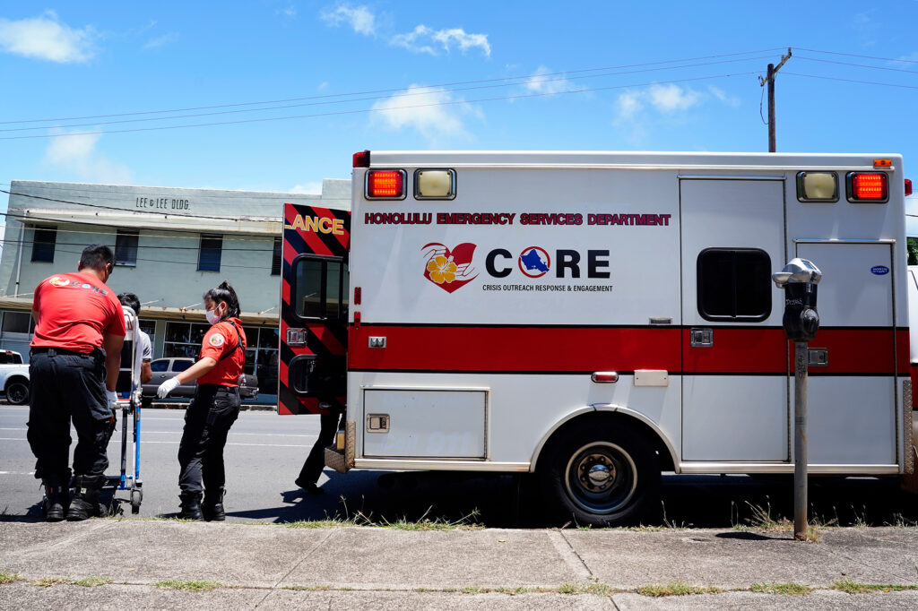 Honolulu C.O.R.E. team members including EMT Taylor Kodani, third left, prepares to move a homeless patient into their ambulance at Kaimuki Community Park Monday, Aug. 19, 2024, in Honolulu. (Kevin Fujii/Civil Beat/2024)