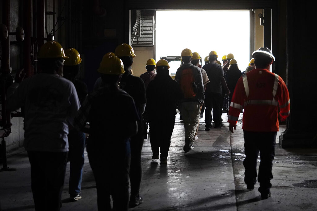 Tour de Trash participants walk through an H-Power building where rubbish is sorted Wednesday, Aug. 28, 2024, in Kapolei. The City and County of Honolulu’s annual tour follows the journey of Oahu residents and visitors’ rubbish, recyclable items and compostable/green waste take through the collection and disposal process. (Kevin Fujii/Civil Beat/2024)