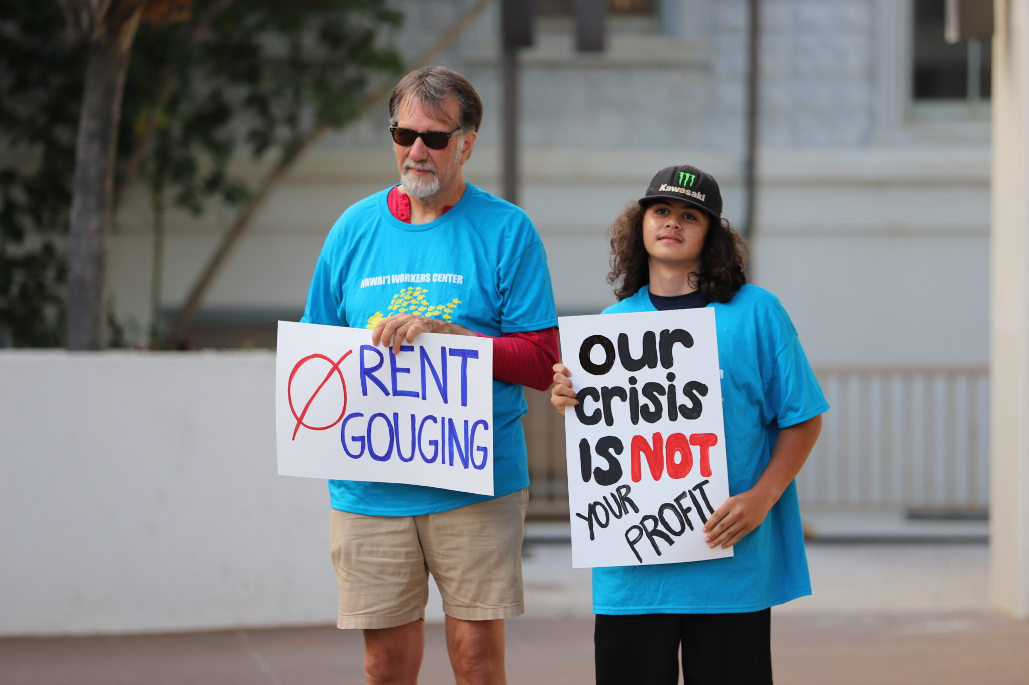 Alan Lloyd, left, of the Maui Tenants and Workers Association, and Samuel Santiago held protest signs in front of the Maui County Building prior to a meeting to discuss a potential bill to regulate rental prices on Maui. (Léo Azambuja/Civil Beat/2024)