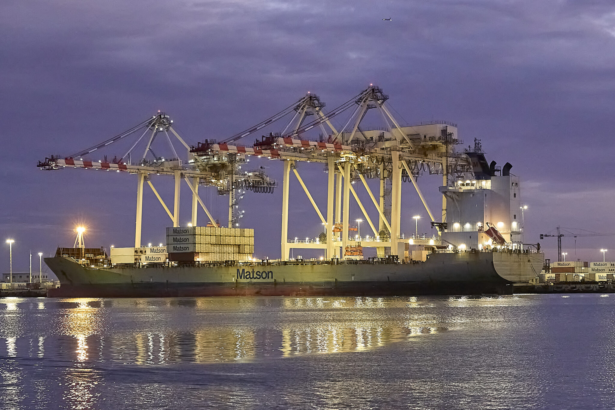 A Matson Container Vessel waits at the Sand Island HQ of Matson Corp. while it is loaded with containers bound for distant shores. Photographed October 28th at dusk. (David Croxford/Civil Beat/2024)