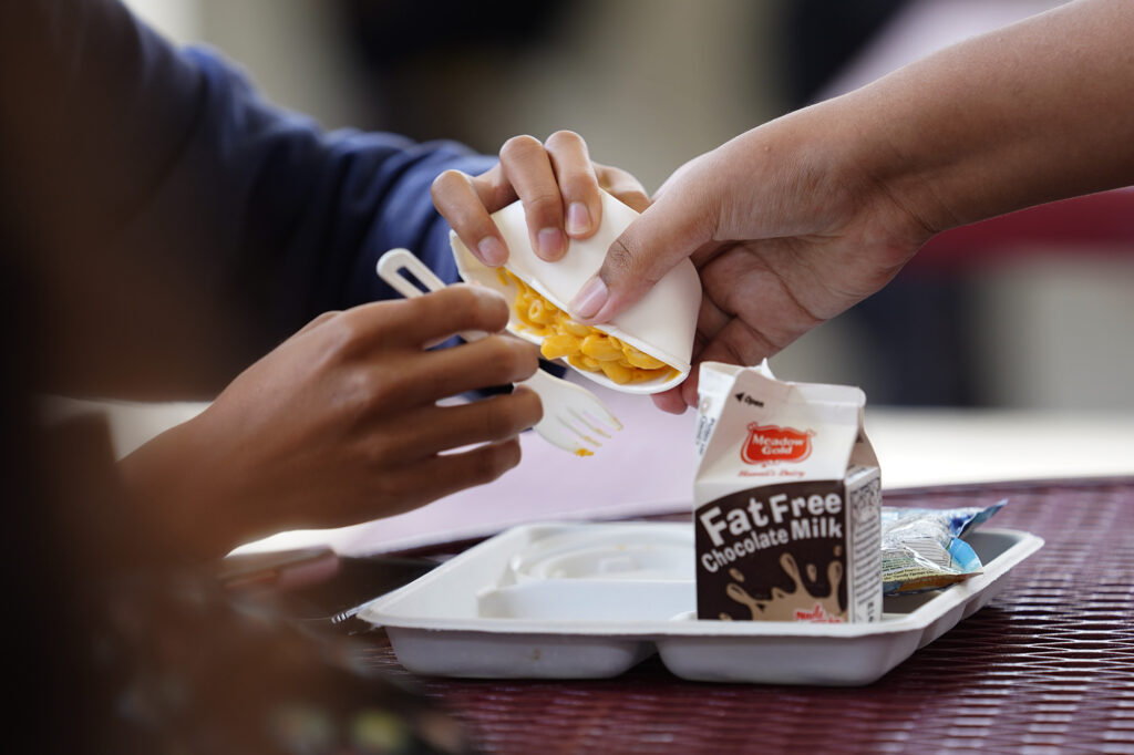 Castle High School students try to squeeze out the mac and cheese of a school lunch Monday, May 5, 2025, in Kāneʻohe. Other options available for lunch on this day included carrots, broccoli, pineapple, juice slush and a dinner roll. (Kevin Fujii/Civil Beat/2025)