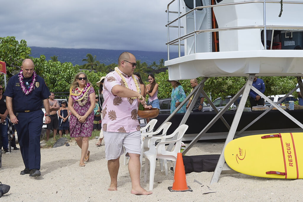 Rachel Able whose daughter drowned at Pine Trees Beach before the Lifeguard  Tower was installed is joined by members of the council and representatives from the mayors office as the tower is blessed on Friday June 13th.(David Croxford/Civil Beat/2025)