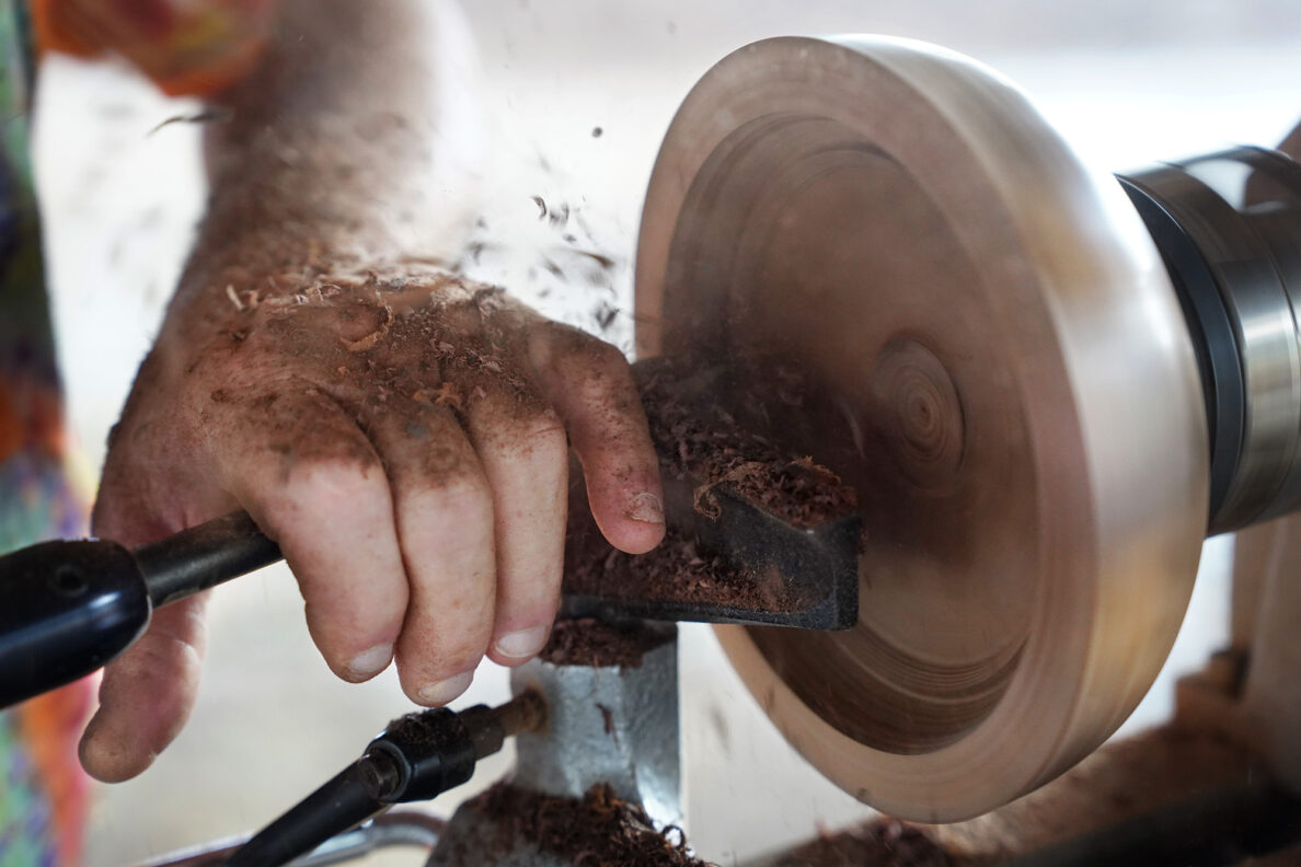 Milo-wood shavings fly out of the interior of a bowl beginning to take shape on woodturner Aaron Hammer’s mobile woodturning studio Wednesday, July 2, 2025, in Kailua. (Kevin Fujii/Civil Beat/2025)