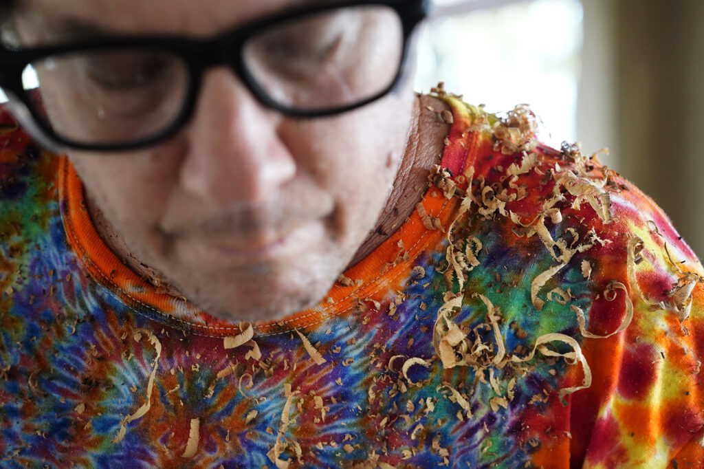 Milo-wood shavings begin to cover woodturner Aaron Hammer while shaping a bowl Wednesday, July 2, 2025, in Kailua. (Kevin Fujii/Civil Beat/2025)