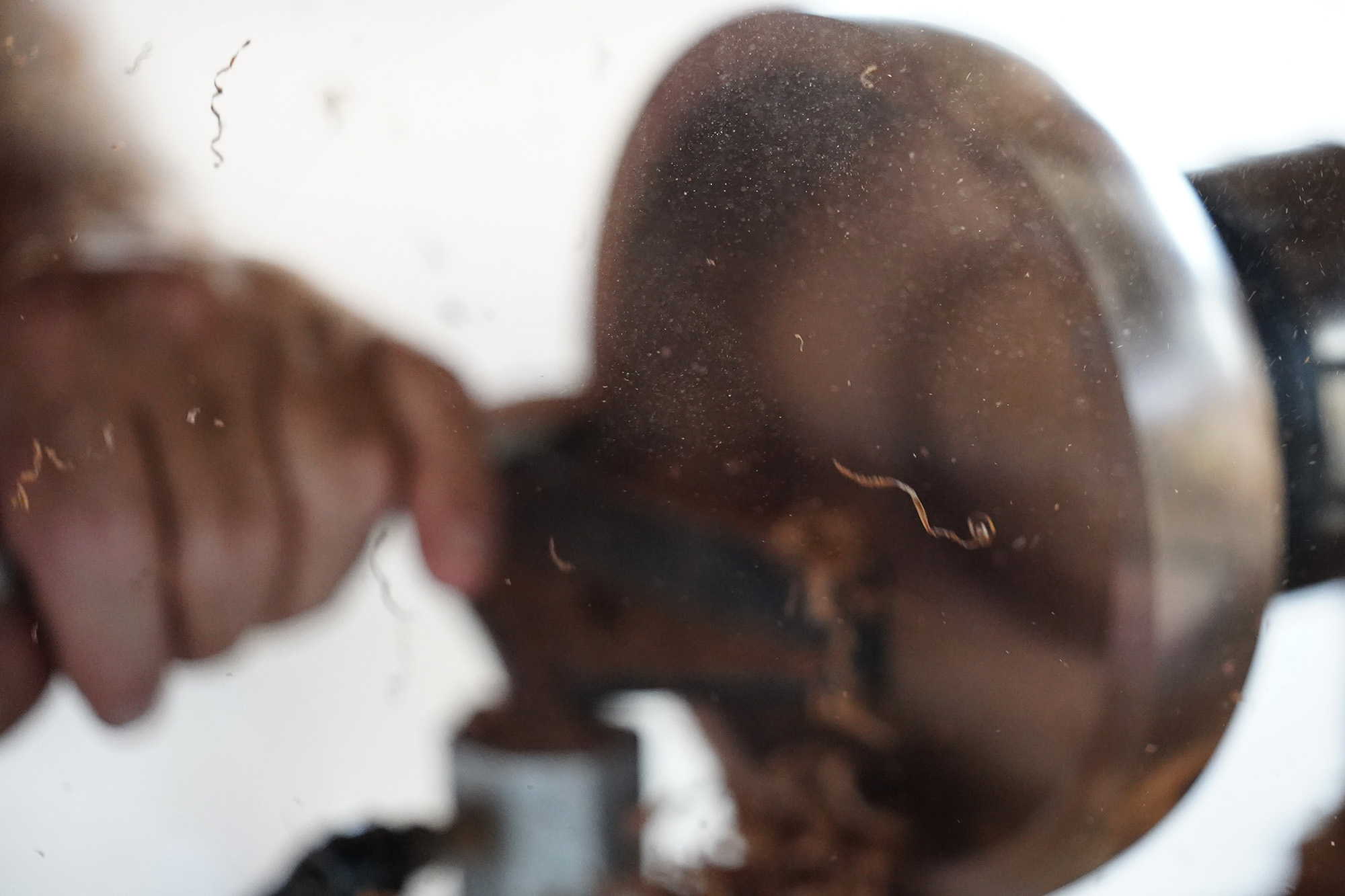 Dust and wood shavings fly out of a milo-wood bowl woodturner Aaron Hammer is creating Wednesday, July 2, 2025, in Kailua. (Kevin Fujii/Civil Beat/2025)