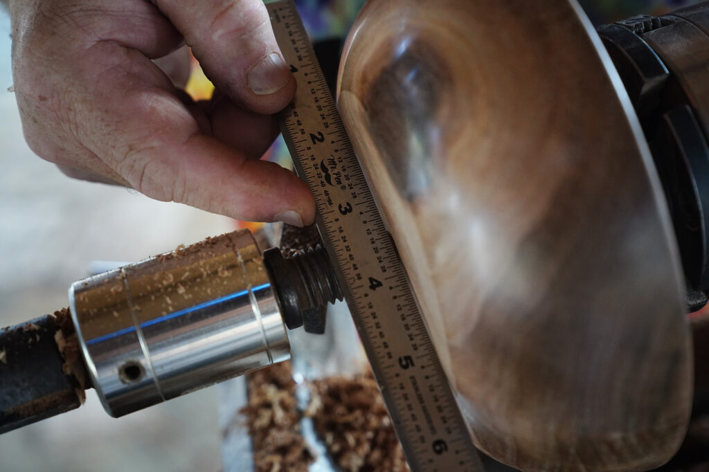 Woodturner Aaron Hammer checks the base of his newly created milo-wood bowl Wednesday, July 2, 2025, in Kailua. The slightly concave base adds stability to his creations. (Kevin Fujii/Civil Beat/2025)