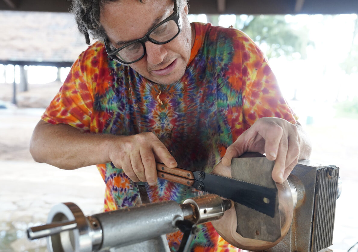 Woodturner Aaron Hammer saws off the last remaining piece of the foot Wednesday, July 2, 2025, in Kailua. This section was used to attache the tail of his lathe to the spin the bowl. (Kevin Fujii/Civil Beat/2025)