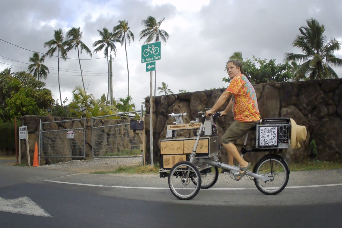 Woodturner Aaron Hammer rides back home after creating a milo-wood bowl at Kailua Beach Park on his mobile studio Wednesday, July 2, 2025, in Kailua. “How many woodturners can say, ‘I’m gonna take my lathe out for a ride?’” Hammer jokes. Still image taken from video. (Kevin Fujii/Civil Beat/2025)