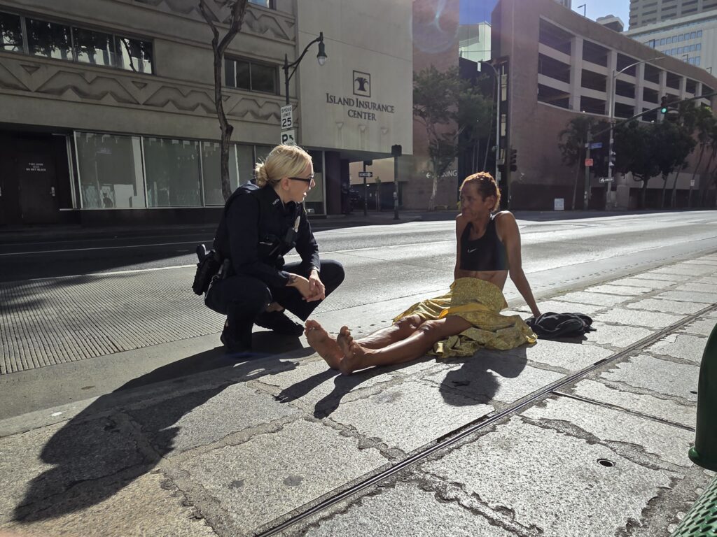 Honolulu Police Officer speaks with a woman named Helen before giving her a warning about violating Honolulu laws that prohibit sitting or lying on public sidewalks.
