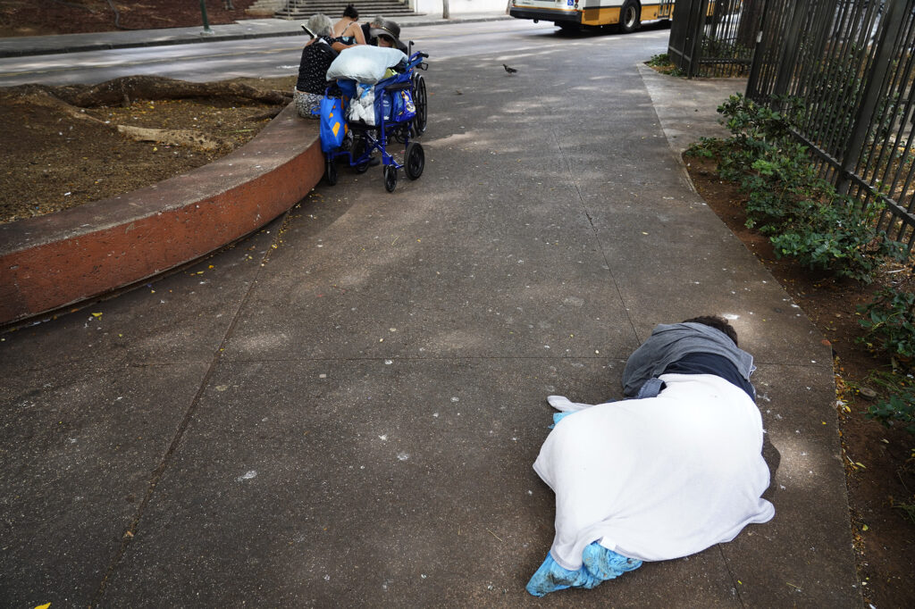 A homeless woman sleeps on a Chinatown sidewalk Tuesday, Nov. 4, 2025, in Honolulu. (Kevin Fujii/Civil Beat/2025)