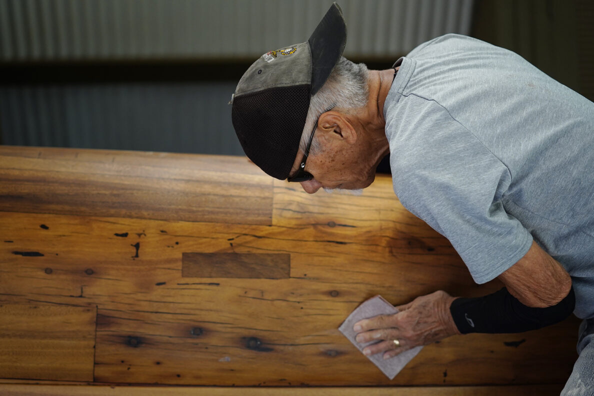 Billy Richards prepares Prince Jonah Kūhiō Kalanianaʻole’s a‘a for its final coat Monday, Nov. 3, 2025, at the Bishop Museum in Honolulu. The 40-foot racing canoe will return to the water for the first time in more than a decade. (Kevin Fujii/Civil Beat/2025)