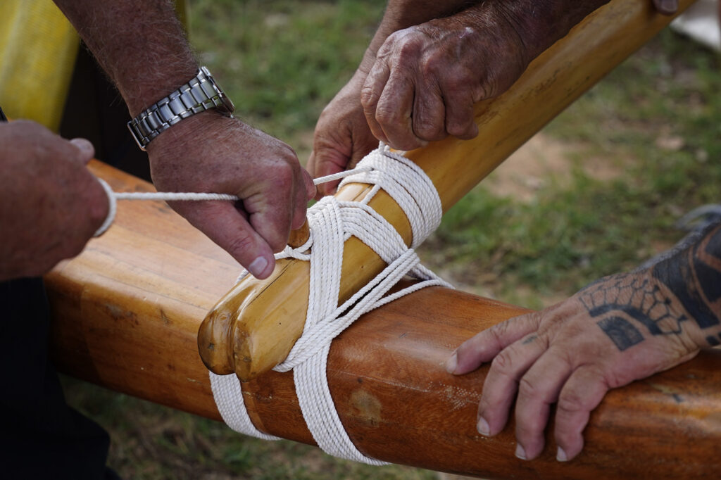 Lanalana, or attaching the ama (outrigger float) to the ‘iako  (boom), prepares Prince Prince Jonah Kūhiō Kalanianaʻole’s racing canoe, the A‘a, at Ke‘ehi Lagoon Friday, Nov. 7, 2025, in Honolulu. (Kevin Fujii/Civil Beat/2025)