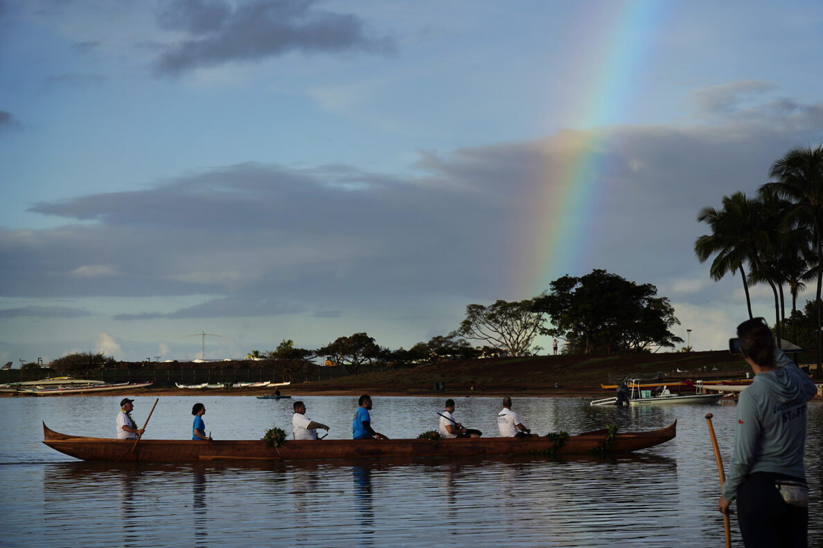 The A‘a returns to shore after its ceremonial blessing and paddle at Ke‘ehi Lagoon Saturday, Nov. 8, 2025, in Honolulu. The koa wa‘a was Prince Jonah Kūhiō Kalanianaʻole’s famous koa racing canoe. 
A light rain fell on the shore creating a perfect rainbow over the crowd. (Kevin Fujii/Civil Beat/2025)