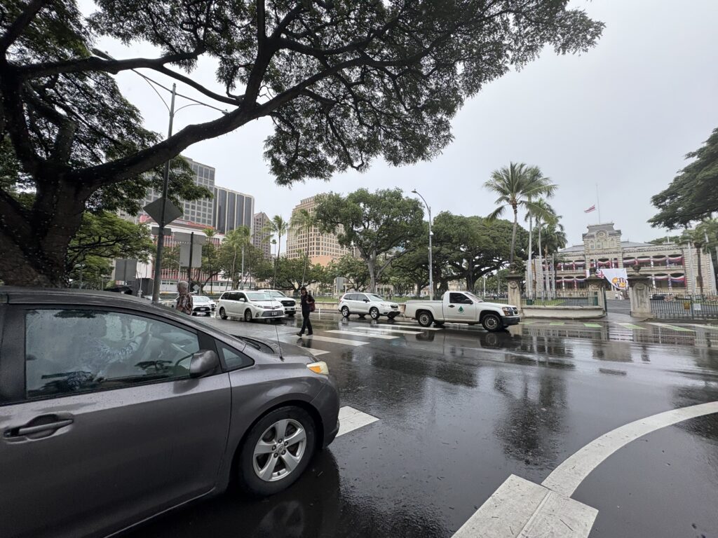 ʻIolani Palace crosswalk sees plenty of pedestrians amid busy traffic.