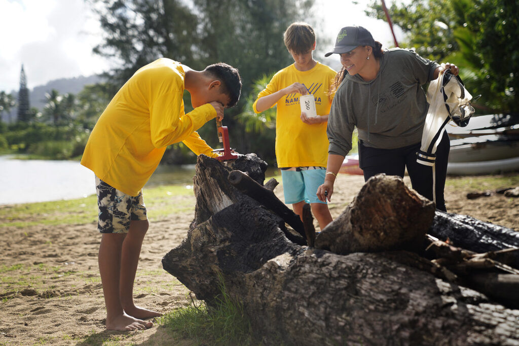 Namahana School students Alex Acob, 12, from left, Hurley Haneberg, 12, and Na Maka Onaona volunteer Hulali Soza get a closer view of plankton during an ʻāina based learning day at Hanalei Bay Wednesday, Nov. 19, 2025, in Hanalei. (Kevin Fujii/Civil Beat/2025)