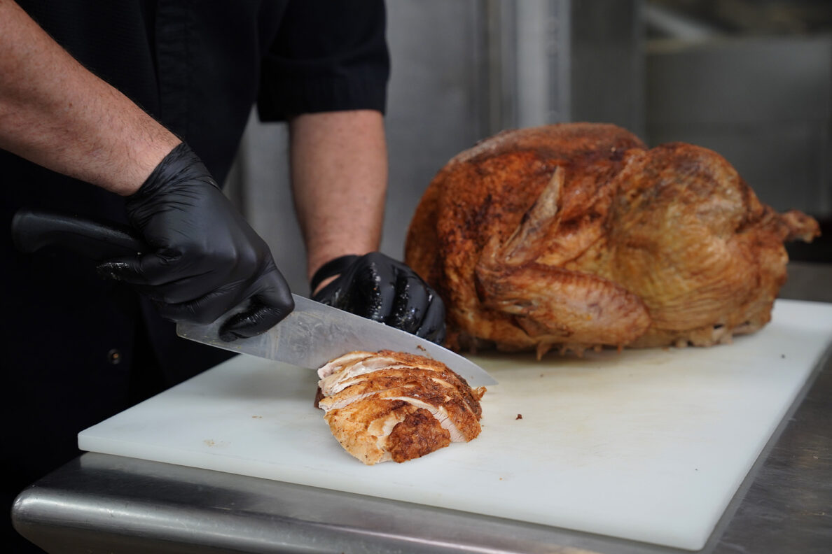Hilton Hawaiian Village Executive Sous Chef Joseph “JJ” Reinhart slices a turkey breast for part of the 450 Thanksgiving meals Tuesday, Nov. 25, 2025, in Honolulu. This marks the 30th year the hotel kitchen donates to the Institute for Human Services (IHS). (Kevin Fujii/Civil Beat/2025)