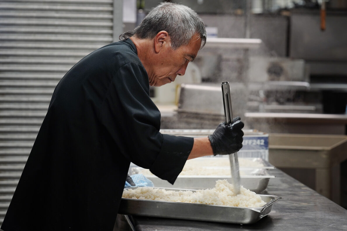 Hilton Hawaiian Village kitchen cook Yiukwan “Kenny” Tsang mixes steamed white rice which will be included in the 450 Thanksgiving meals Tuesday, Nov. 25, 2025, in Honolulu. 150 pounds of stuffing, mashed potatoes and rice will be included in each meal. This marks the 30th year the hotel kitchen donates to the Institute for Human Services (IHS). (Kevin Fujii/Civil Beat/2025)