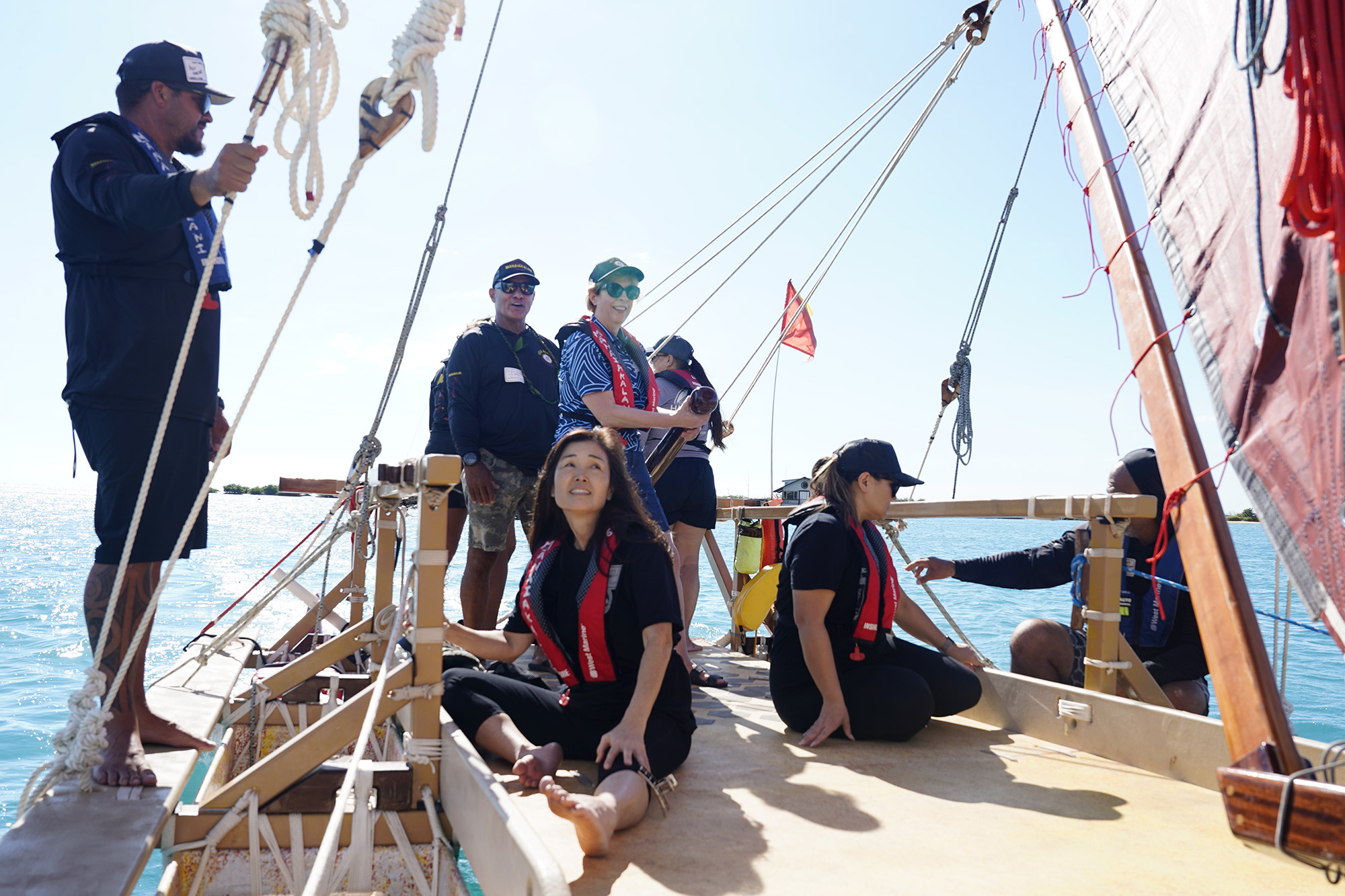 Lele Aloha’s Archie Kalepa guides one of Maui’s Complex Area Superintendents Rebecca Winkie on the Mānaiakalani voyaging canoe’s hoe uli (steering paddle or rudder) during the Ho‘ākea Honolulu hands-on learning and experiencing event centered around traditional Hawaiʻian navigation and voyaging canoes Wednesday, Dec. 3, 2025, in Honolulu. Hawaiʻian voyaging traditions, cultural practices and ʻāina-based learning pairs with DOE curriculum to create a “Navigator Mindset”. Hugo Sanchez, from left, Brittany Kamai, Kalepa, Terry Oshiro, Winkie, Tanya Flores, Nana Ching and Christian Hett. (Kevin Fujii/Civil Beat/2025)