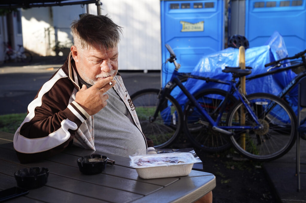 Aaron Lapham works on finishing his cigarette before breakfast at the A‘ala Respite Center Monday, Dec. 8, 2025, in Honolulu. The former bank building turned medical facility is attached to a kauhale to help homeless get well and back on their feet. (Kevin Fujii/Civil Beat/2025)