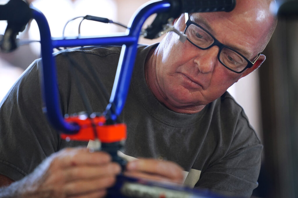 Volunteer Tom Nooney of Olinda tightens brake cables during one of Jim Falk’s annual Christmas Kids Bike Build days Saturday, Dec. 6, 2025, in Puʻunēnē. (Kevin Fujii/Civil Beat/2025)