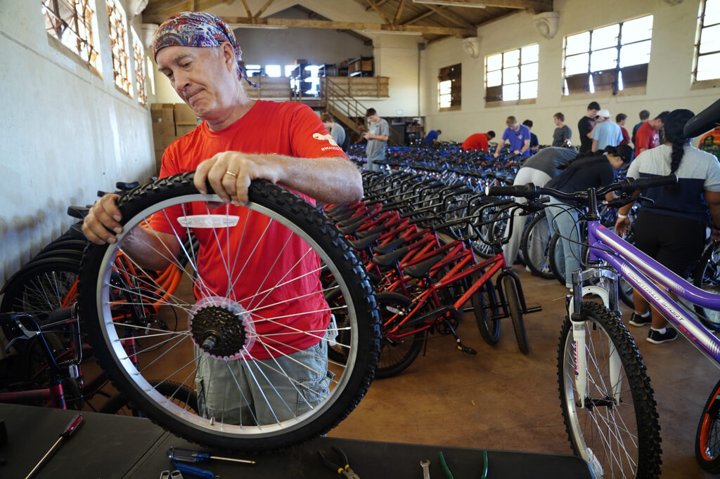 Volunteer Jerry Rice of Wailuku replaces an inner tube during one of four Jim Falk’s annual Christmas Kids Bike Build days Saturday, Dec. 6, 2025, in Puʻunēnē. This is Rice’s fourth year volunteering. “It’s surprising how many new bikes have flat tires,” Rice said. (Kevin Fujii/Civil Beat/2025)
