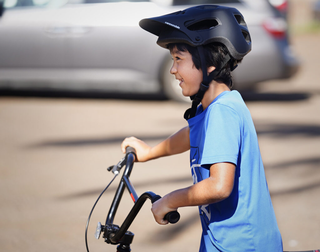 Elisha Oshima, 9, smiles to his mom wearing a new helmet and trying out his new bike during Jim Falk’s annual Christmas Kids Bike Build takes place Saturday, Dec. 6, 2025, in Puʻunēnē. Approximately 450 new bicycles are built and distributed in Maui County. Oshima and his family have been volunteering with the bike build and their church. (Kevin Fujii/Civil Beat/2025)