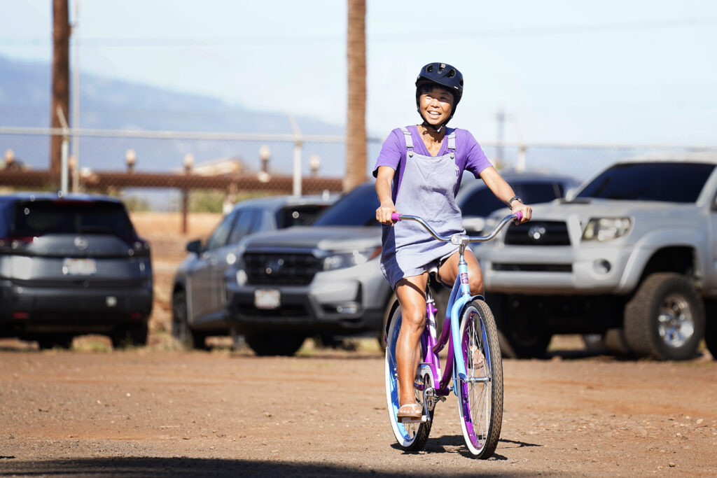 “I feel like a teenager again!” Mayumi Oshima said after taking her new bike for a spin during one of four Jim Falk’s annual Christmas Kids Bike Build days Saturday, Dec. 6, 2025, in Puʻunēnē. Approximately 450 new bicycles are built and distributed in Maui County. Oshima and her sons have been volunteering with the bike build and their church. (Kevin Fujii/Civil Beat/2025)