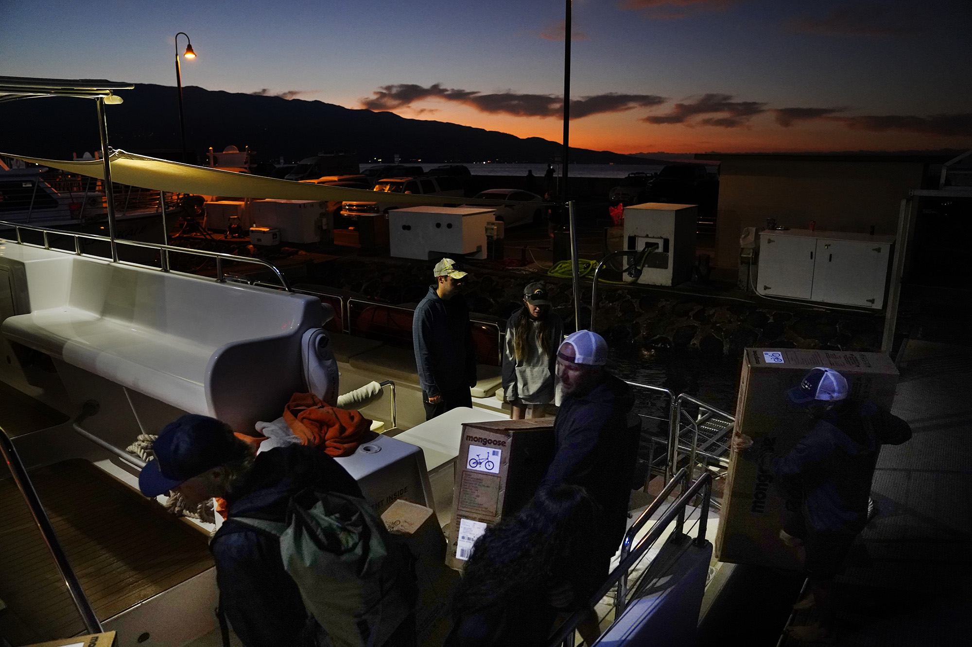 The sun rises behind Haleakalā as the Trilogy crew, volunteers and Krank Cycles Maui employees load boxed bikes onto the catamaran for Jim Falk’s annual Christmas Kids Bike Build Wednesday, Dec. 10, 2025, in Māʻalaea Harbor. These bikes are destined for Kaunakakai, Molokaʻi, where 40 new bicycles will be built and distributed to keiki on Molokaʻi for Christmas. (Kevin Fujii/Civil Beat/2025)