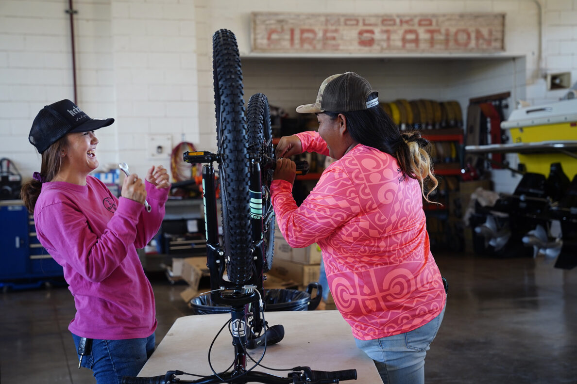 Bayer employees Keeya Bicoy, left, and Ambrosialynn Casil-Dudoit share a laugh while attaching pedals to a bike during Jim Falk’s annual Christmas Kids Bike Build Wednesday, Dec. 10, 2025, in Kaunakakai, Molokaʻi. Approximately 450 new bicycles are built and will distributed to keiki in Maui County. (Kevin Fujii/Civil Beat/2025)