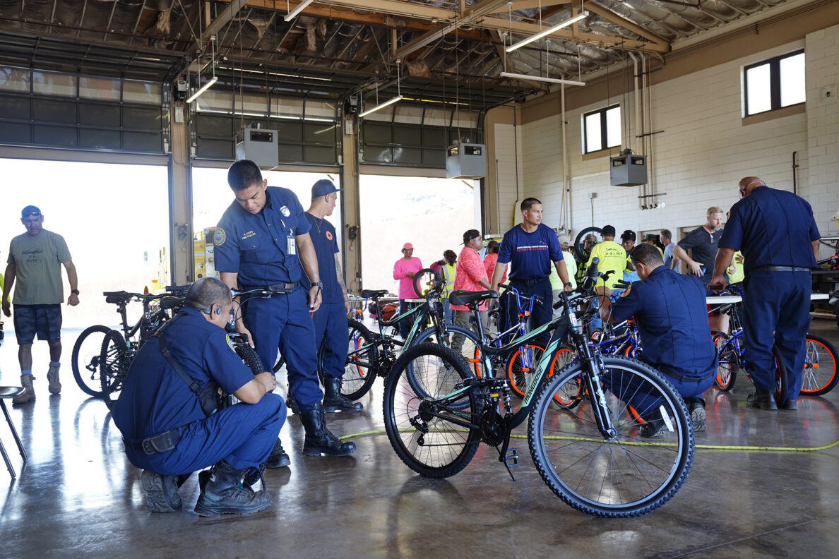 Kaunakakai Fire Station fire fighters offer a location for Jim Falk’s annual Christmas Kids Bike Build and fill tires with air after returning from a call Wednesday, Dec. 10, 2025, in Kaunakakai, Molokaʻi. Approximately 450 new bicycles are built and will distributed to keiki in Maui County. (Kevin Fujii/Civil Beat/2025)
