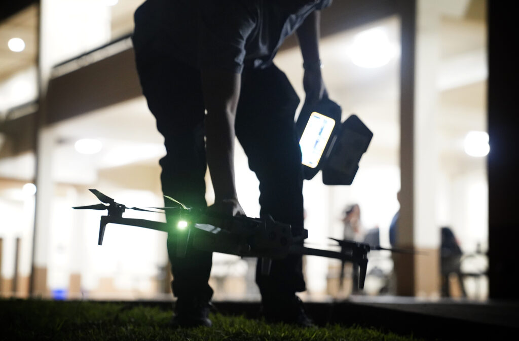 A drone pilot picks up his craft before Department of Law Enforcement Director Mike Lambert takes journalists on a ride along Wednesday, Dec. 31, 2025, in Waipahu. New laws, the use of aerial drones and citizens heeding the dangers of fireworks noticeably  curbed the annual personal pyrotechnics. (Kevin Fujii/Civil Beat/2025)