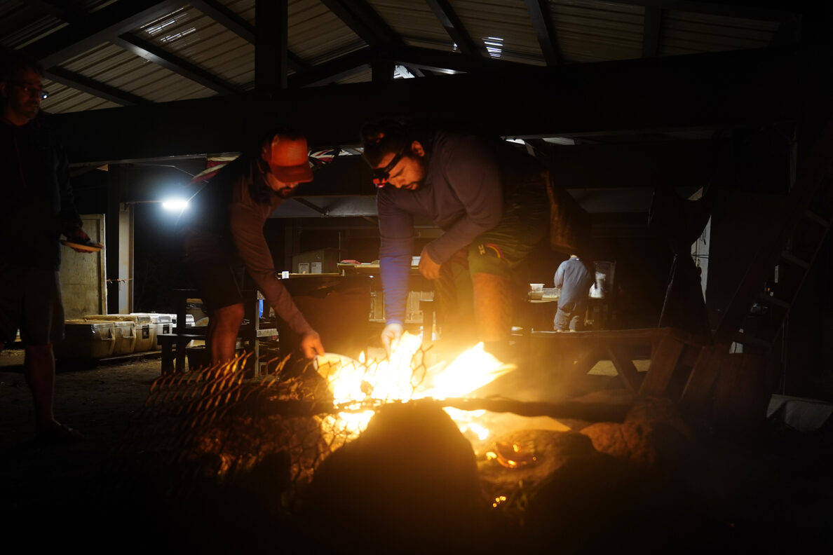 Protect Kahoʻolawe ʻOhana (PKO) Kawai Lu‘uwai, left, and Kaipu Keala burn paper rubbish after dinner Monday, Jan. 5, 2026, in Hakioawa. PKO celebrates the 50th year of sovereign land. (Kevin Fujii/Civil Beat/2026)