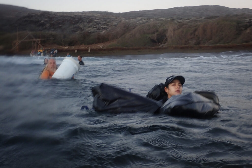 Protect Kahoʻolawe ʻOhana (PKO) Kaulu Lu‘uwai swims ukana (luggage, bags) toward the zodiac Wednesday, Jan. 7, 2026, in Hakioawa. Without a dock or pier, getting to Hakioawa requires getting wet. (Kevin Fujii/Civil Beat/2026)