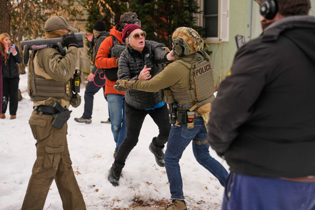 A woman gets into an altercation with a federal immigration officer as officers make an arrest Sunday, Jan. 11, 2026, in Minneapolis. (AP Photo/John Locher)