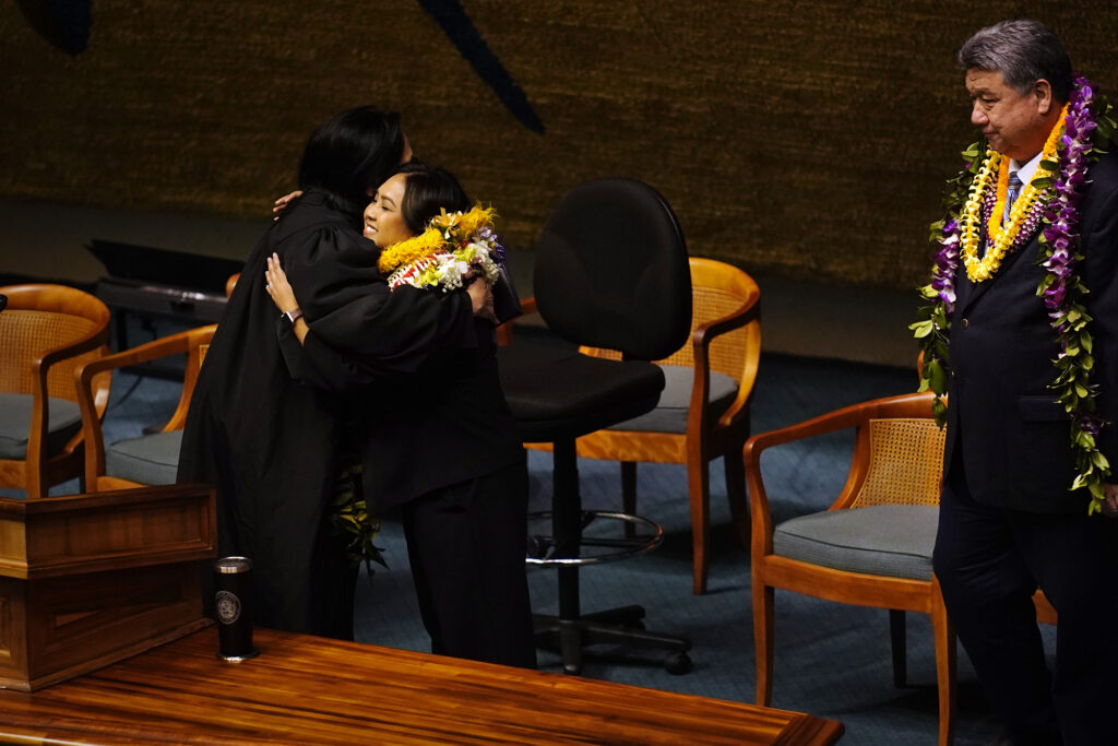 Acting Chief Justice of the Hawaiʻi Supreme Court Sabrina McKenna hugs Sen. Rachele Lamosao after swearing her in during the opening of the Hawaiʻi State Legislature Wednesday, Jan. 21, 2026, in Honolulu. Senate President Ron Kouchi looks on. Gov. Josh Green appointed Lamosao on Dec. 3, 2025. (Kevin Fujii/Civil Beat/2026)