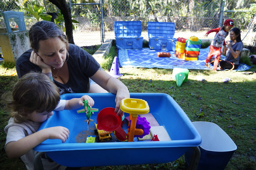 Finn Dillen, 2 1/2, plays with water toys with his mother Jessica Dillen at Keiki O Ka ʻĀina class Tuesday, Jan. 27, 2026, in Hauʻula. Federal funding cuts for Native Hawaiian education programs will significantly impact family-child interaction learning programs (FCILs) serving kids ages 0 to 5. The programs primarily target rural and Native Hawaiian communities who have limited early education/childcare options. The expected federal cuts will reduce the number of FCIL programs from 60 to 3. (Kevin Fujii/Civil Beat/2026)