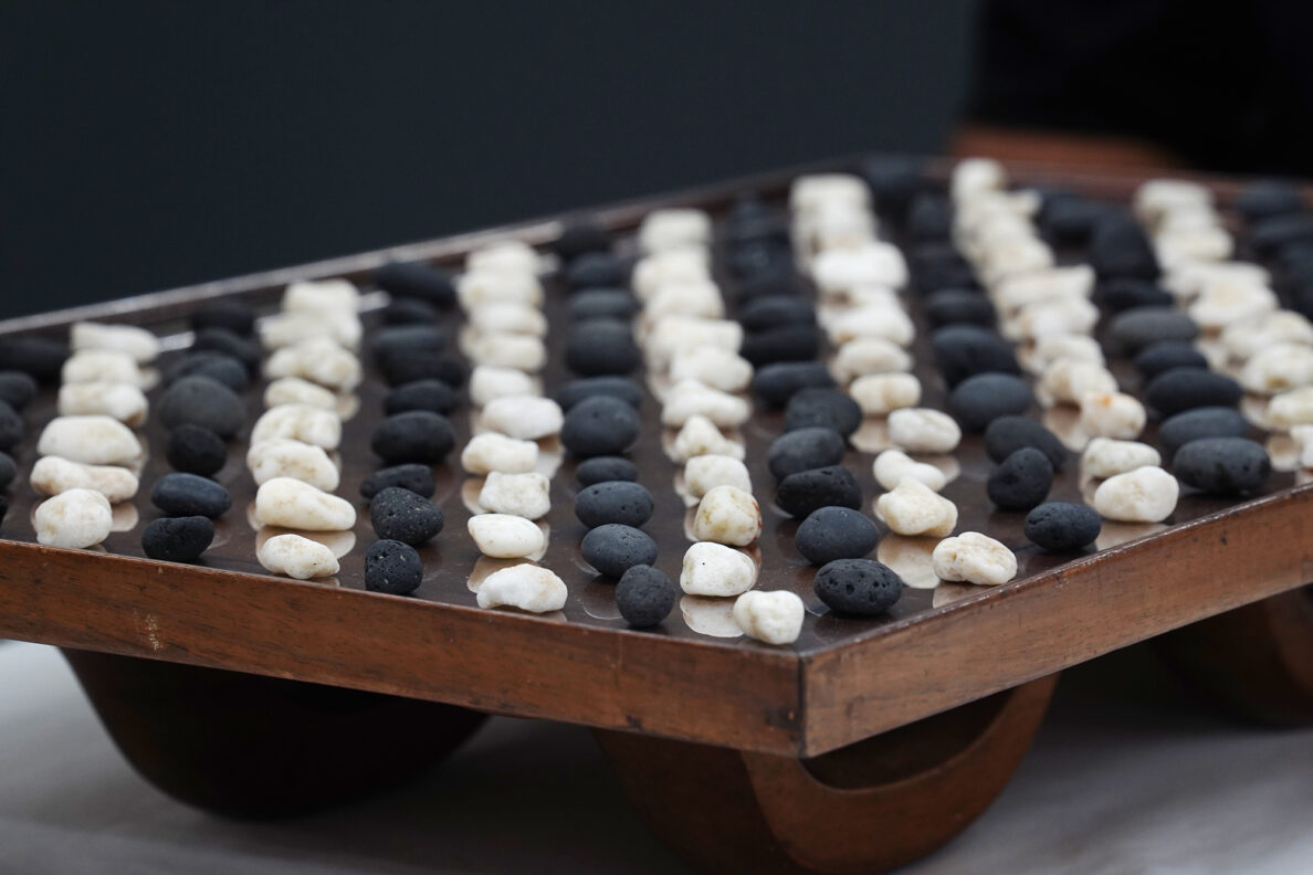 Kōnane game pieces are placed atop the kūpuna papamu Friday, Jan. 30, 2026, at the Bishop Museum in Honolulu. The black game pieces are basalt called 'ili'ili 'ele'ele. ‘Ili'ili ke'oke'o are the white coral game pieces. (Kevin Fujii/Civil Beat/2026)